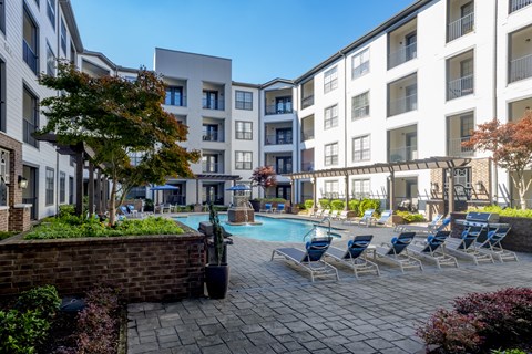 a swimming pool with chaise lounge chairs in front of an apartment building